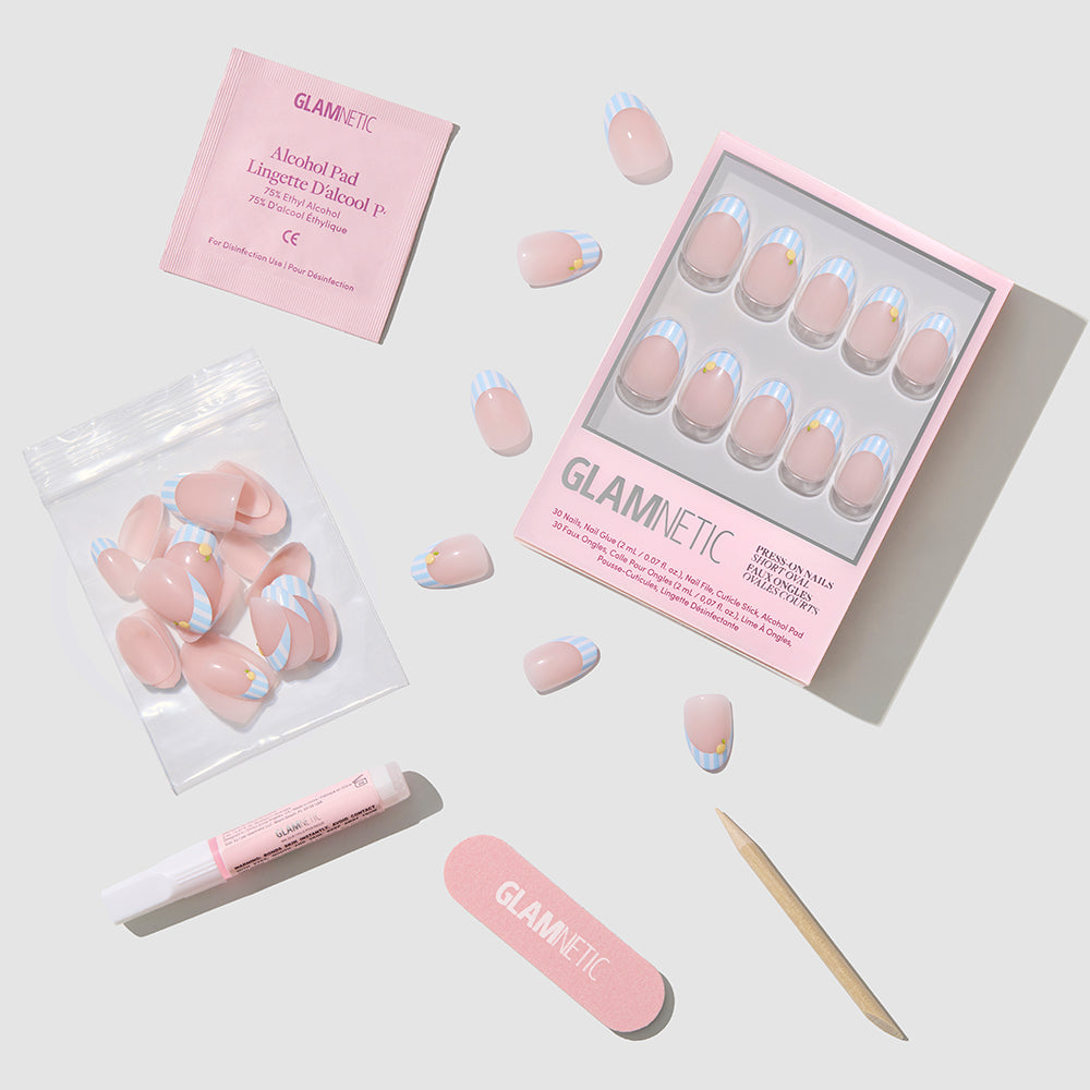 A flat lay of the glamnetic Summer Fresco press-on nail kit, featuring short oval nails with blue and white tips, loose nails, nail glue tube, mini file, cuticle stick, alcohol pad, and a clear pouch—perfect for summer. - Product image