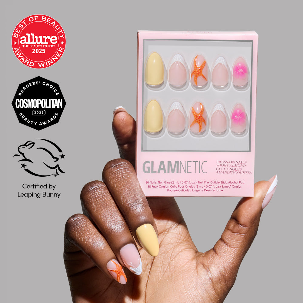 A hand with pastel and floral-patterned short almond press-on nails holds a box of glamnetic Sunset Tide press-on nails. Logos for Allure, Cosmopolitan, and Leaping Bunny are visible on the left side of the image.