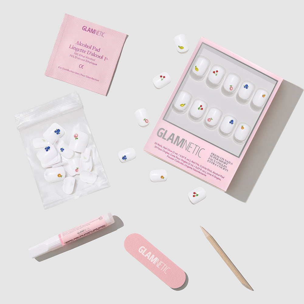 The glamnetic Sweet Picks set includes super short press-on nails with colorful 3D dot art, a pink nail file, wooden cuticle stick, nail glue, alcohol pad packet, and extra nails displayed on a light gray background. - Product image