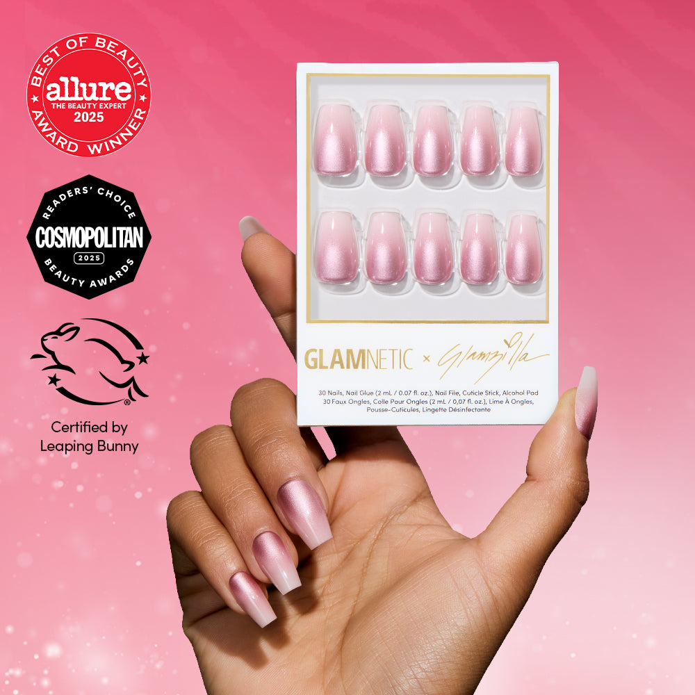 A hand with long, pink, glossy ombré nails holds a box of glamnetic EVERYDAY BEAUTY QUEEN coffin press-ons. The background is pink, featuring award badges and a “Certified by Leaping Bunny” cruelty-free logo on the left.