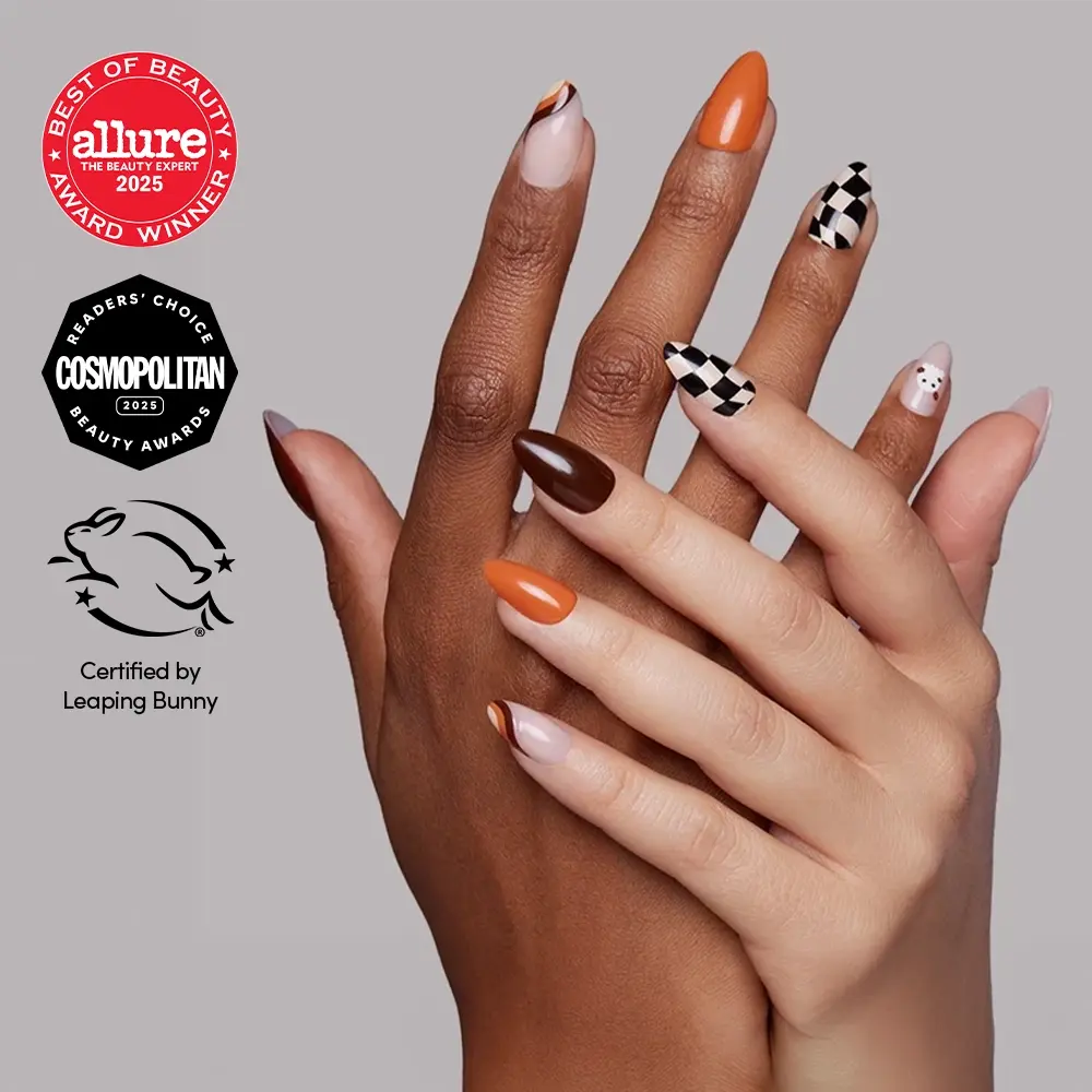 Two hands show off glamnetic’s “Fall Boo” press-on nails in a stunning array of orange, brown, nude, and checkered patterns for a salon-quality fall mani at home. Beauty award logos and the Leaping Bunny cruelty-free certification are visible on the left side.