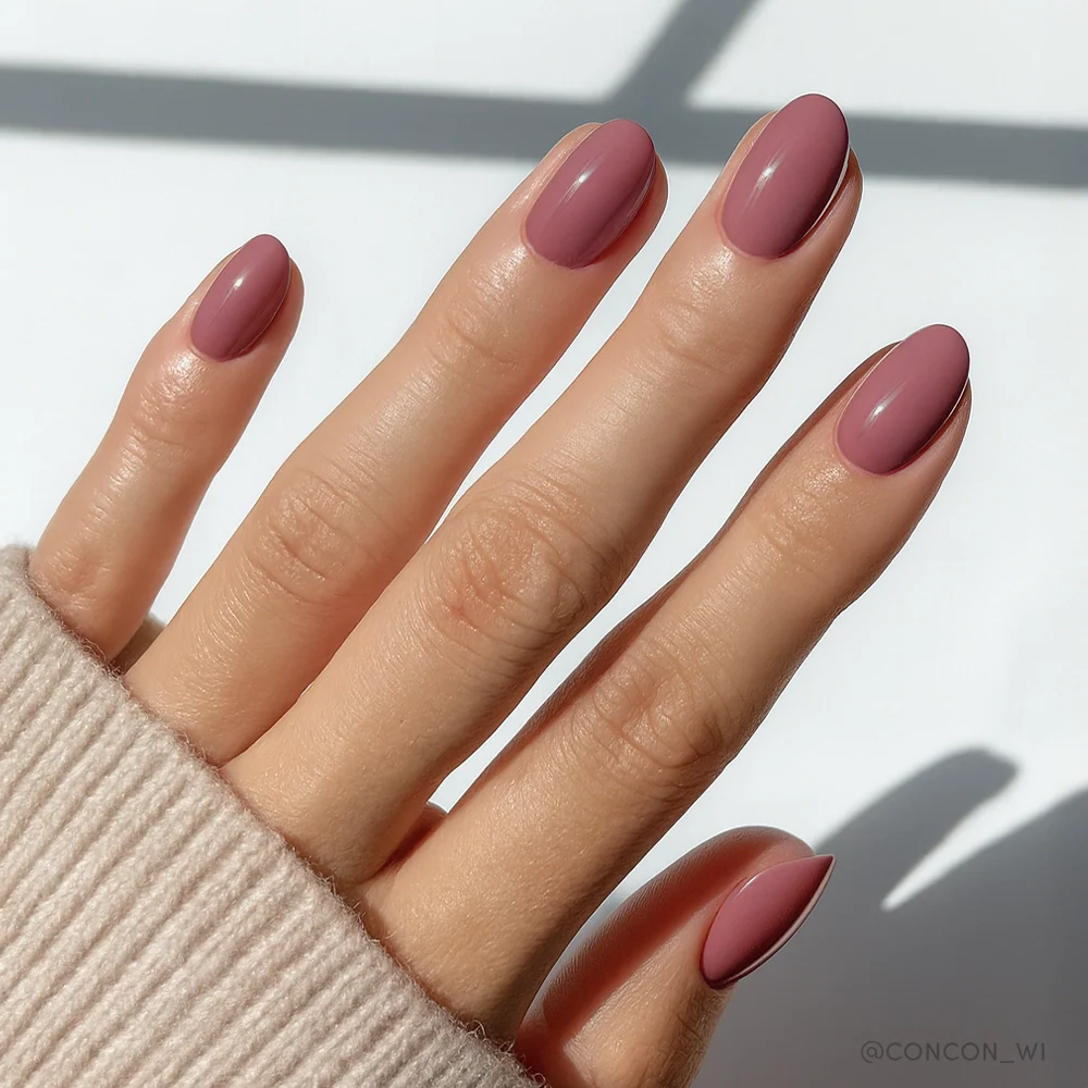 Fall Mauve - A hand with almond-shaped nails in a solid mauve color, showcasing a Fall Mauve nail set by Glamnetic.