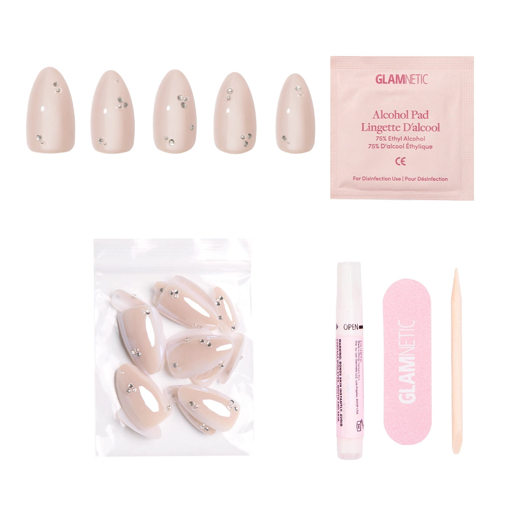 The glamnetic First Dance vegan nude nail set includes small rhinestones, an alcohol pad, a pink nail file, a wooden cuticle stick, nail glue, and extra nails in a plastic pouch—all arranged on a white background. - Product image