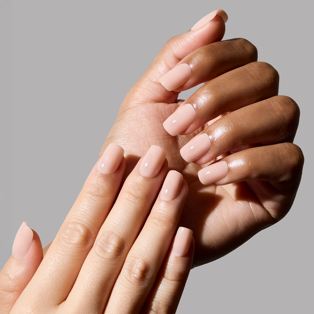 Close-up of two hands with light pink nail polish on a gray background - Product image