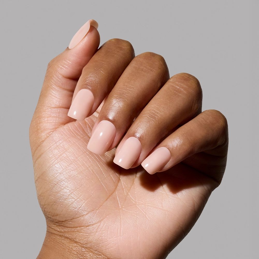 Close-up of a hand with light pink nail polish on a gray background - Product image