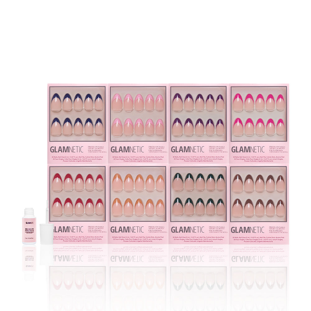 Nine pink boxes of glamnetic French Tip Collection press-on nails, featuring short almond and French tip styles, are arranged in a grid. A small bottle of glamnetic nail glue sits left of the reusable nails on a white background. - Product image
