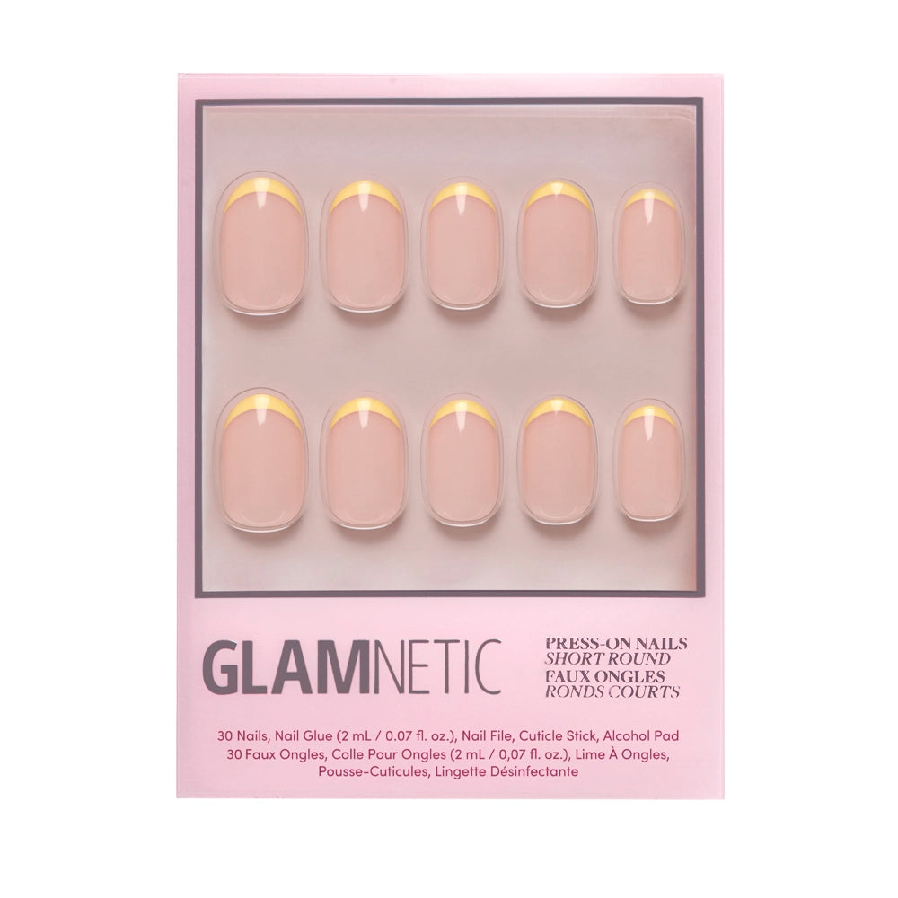 A pink glamnetic box displays the French Butter Press-On Nail Set: 10 short, round nails with a nude base and pastel yellow French tips. Includes nail glue, file, cuticle stick, and alcohol pad for salon-quality durability. - Product image