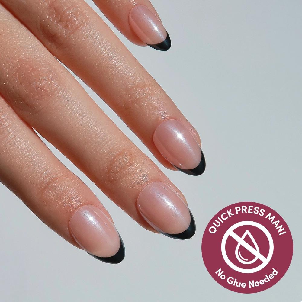A hand shows off glamnetic’s French Noir almond nails with a nude base and black French tips. A circular icon featuring a crossed-out glue bottle highlights Quick Press Mani, indicating these are no-glue press-ons.