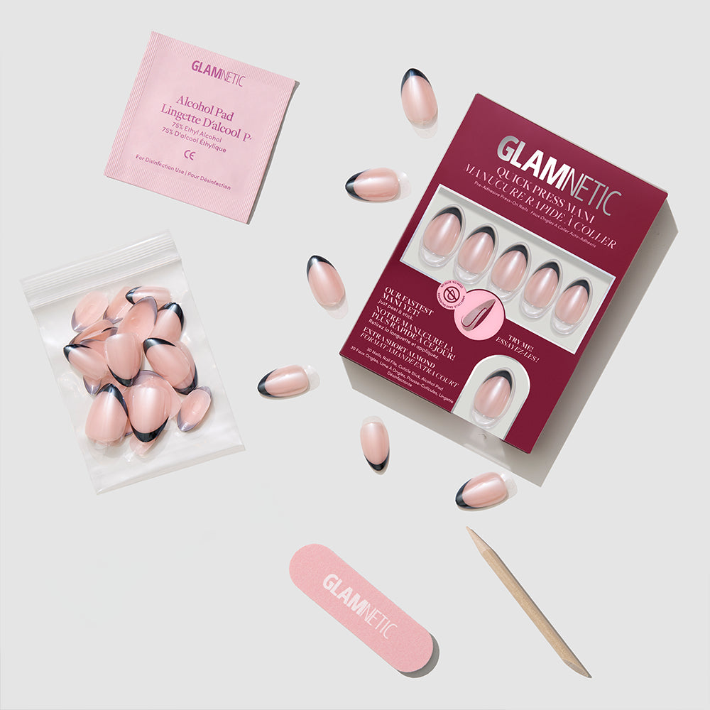 The glamnetic French Noir press-on nail kit is shown, featuring pink nails with black French tips, nail glue, a pink file, a wooden cuticle stick, an alcohol pad, and extra nails in a clear bag. - Product image