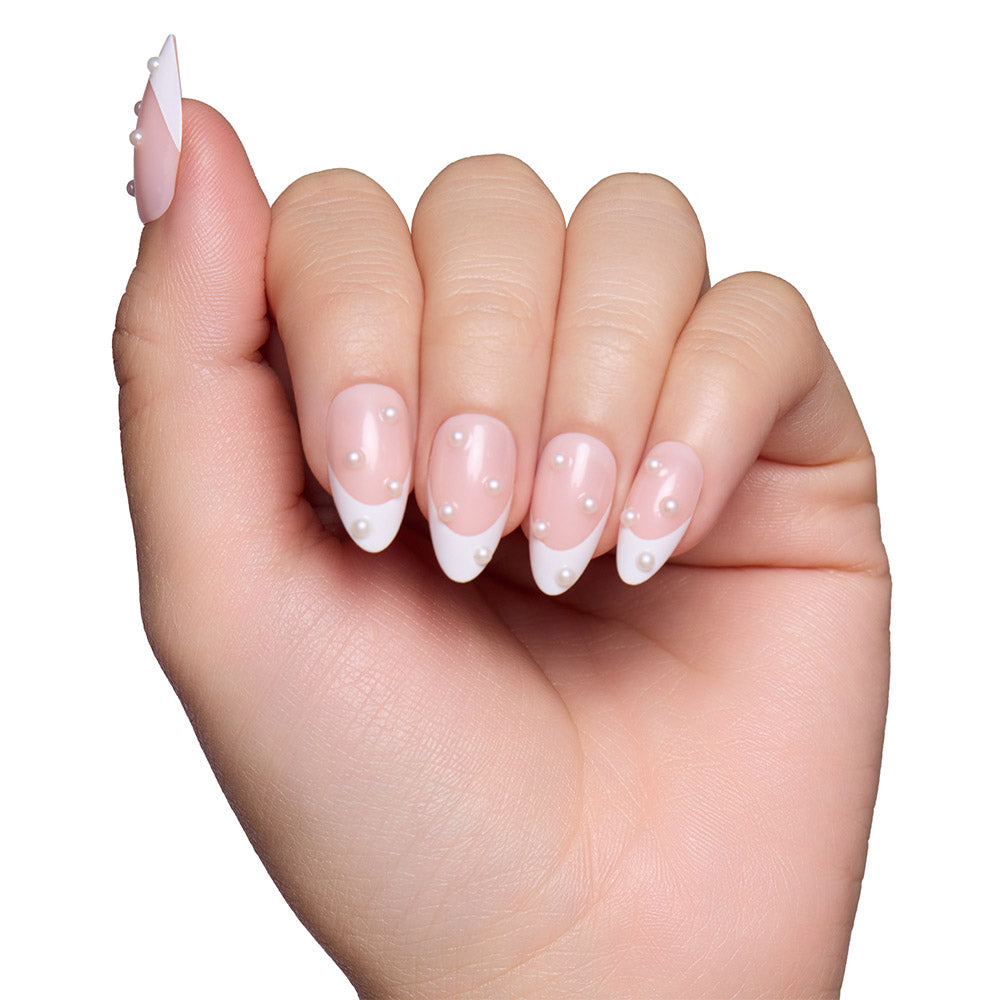 A hand models glamnetic’s French Pearl manicure: short almond nails with white tips and pearl-like accents on a light pink base—an elegant look ideal for bridal events, displayed against a white background. - Product image