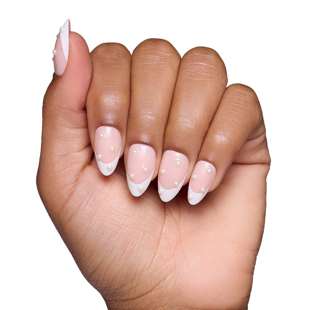 A hand with short almond nails displays the glamnetic French Pearl manicure, featuring modern white tips and pearl-like accents—ideal for bridal events. Set against a plain white background. - Product image