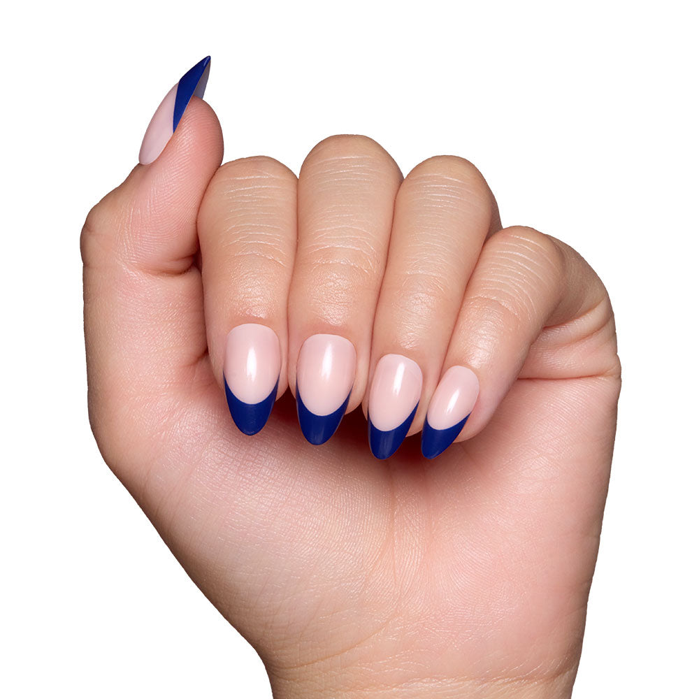 A hand with short almond nails, styled with glamnetics French Riviera—nude base and elegant navy French tips—is shown against a white background. - Product image