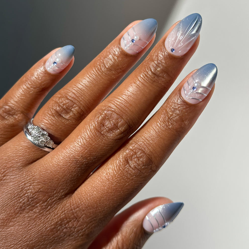 Glamnetic Frosted Crystals almond-shaped salon-quality press-on nails featuring a pink-to-blue gradient, silver line accents, and small blue rhinestone embellishments.