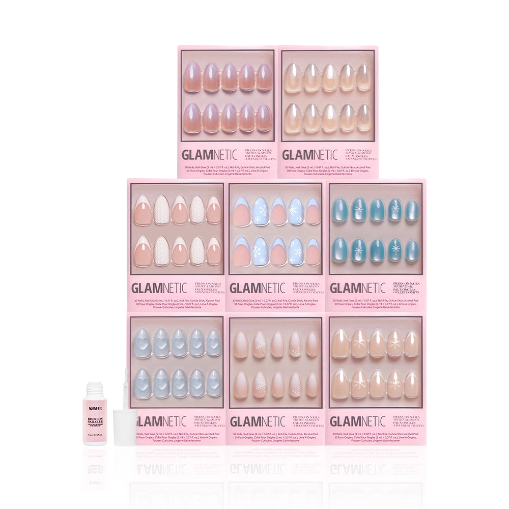 A set of ten glamnetic Frozen Over pink press-on nail kits, featuring short almond nails with unique snowflake designs, arranged in a grid with nail glue on the left against a white background. - Product image