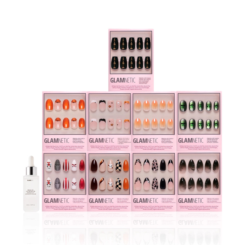 Nine boxes of glamnetic Funhouse Fantasy press-on nails, with spooky and pumpkin designs, are stacked in a pyramid. A bottle of nail glue sits to the left, all displayed against a crisp white background. - Product image