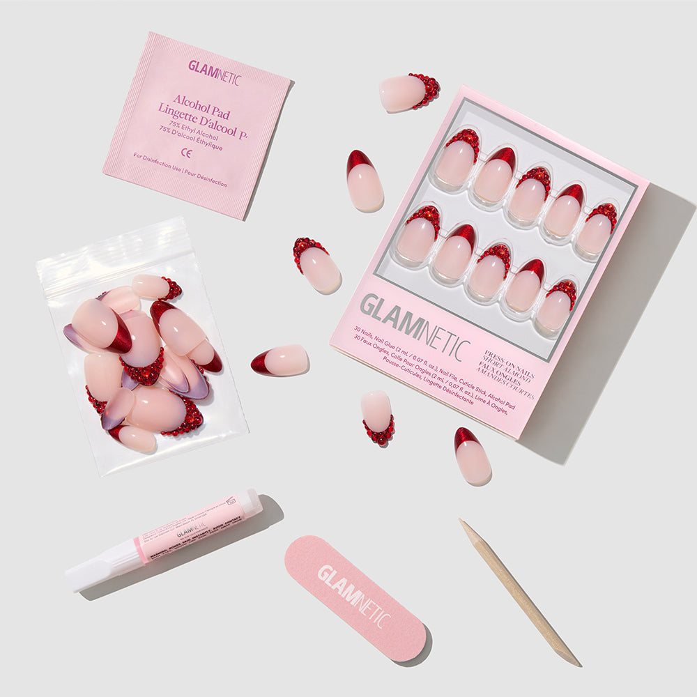 The Garnet press-on nails by glamnetic feature a pink and red gradient with red French tips. The set includes nail glue, alcohol pad, nail file, cuticle stick, extra nails, and is displayed on a white background. - Product image