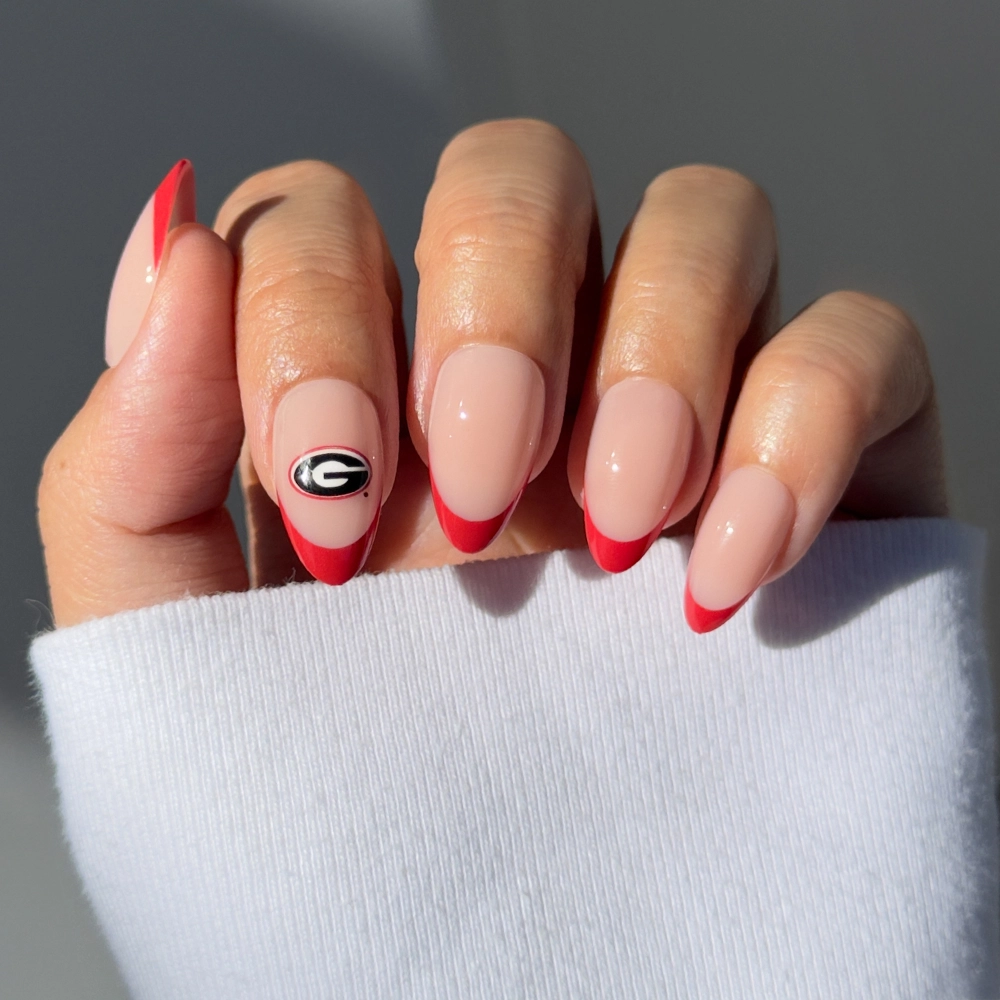 Show off your team spirit with the glamnetic Georgia Bulldogs Press-On Nail Set—long, almond-shaped nails with a nude base, bold red French tips, and a signature black and white team logo for the ultimate fan manicure.