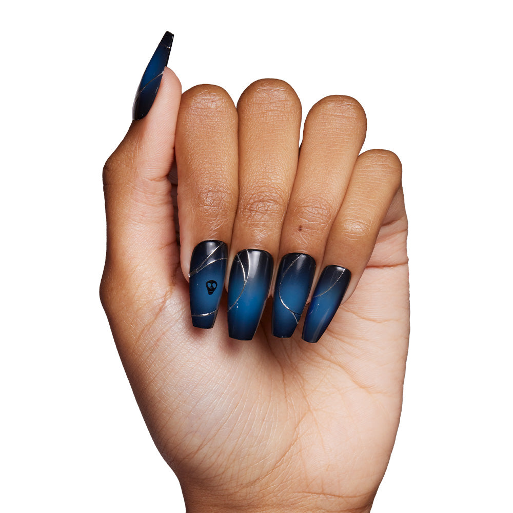 A hand wears long, square-shaped glamnetic Ghost House nails in a glossy dark blue and black ombre with silver lines and a small gem accent, shown against a white background. - Product image