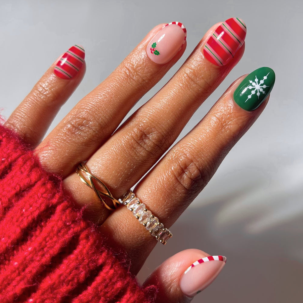 Gifting Season - Glamnetic Gifting Season short oval press-on nails featuring various holiday designs, including red and green stripes, holly berries, and a white snowflake on a green background.