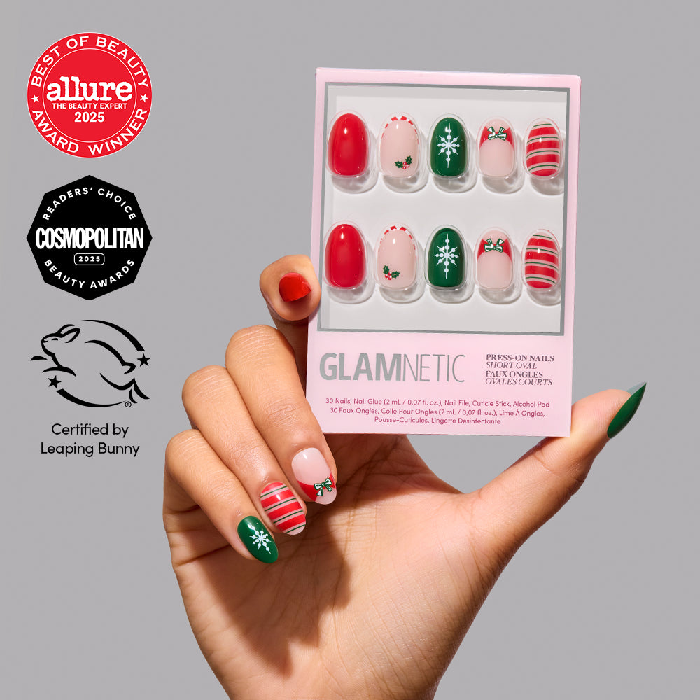 Gifting Season - A hand holds a Glamnetic Gifting Season holiday nail set featuring red, green, and white designs with bows, snowflakes, and holly, along with Allure and Cosmopolitan award logos and a Leaping Bunny certification.