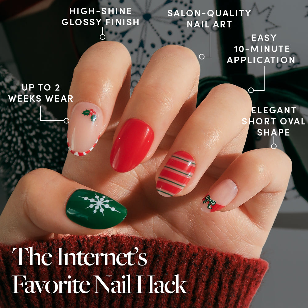 Gifting Season - A hand wears short oval Gifting Season press-on nails by Glamnetic, featuring red, green, and snowflake designs with a glossy finish and easy, long-wear application.