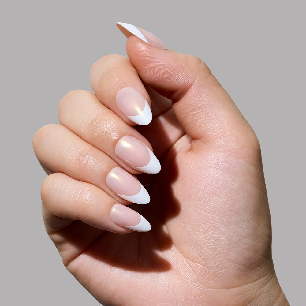 Close-up of a light-skinned hand wearing the full “Give ‘Em Grace” set. The almond-shaped nails have a glossy blush base, white French tips, and a radiant champagne sheen visible in the lighting.
- Product image