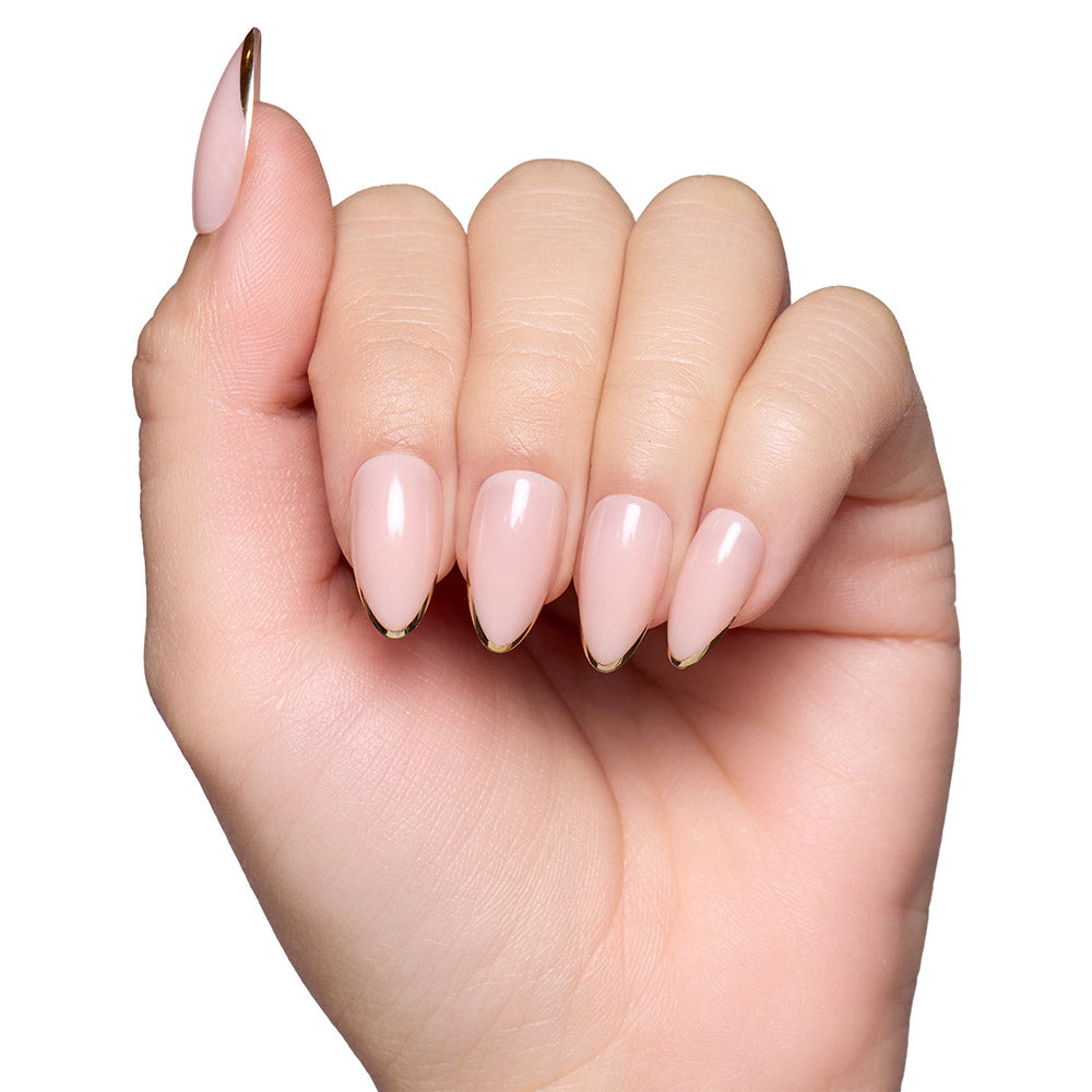 A hand with long, almond nails in glamnetic’s Gold Standard—a glossy light pink set with thin metallic gold tips—shines against a white background. - Product image
