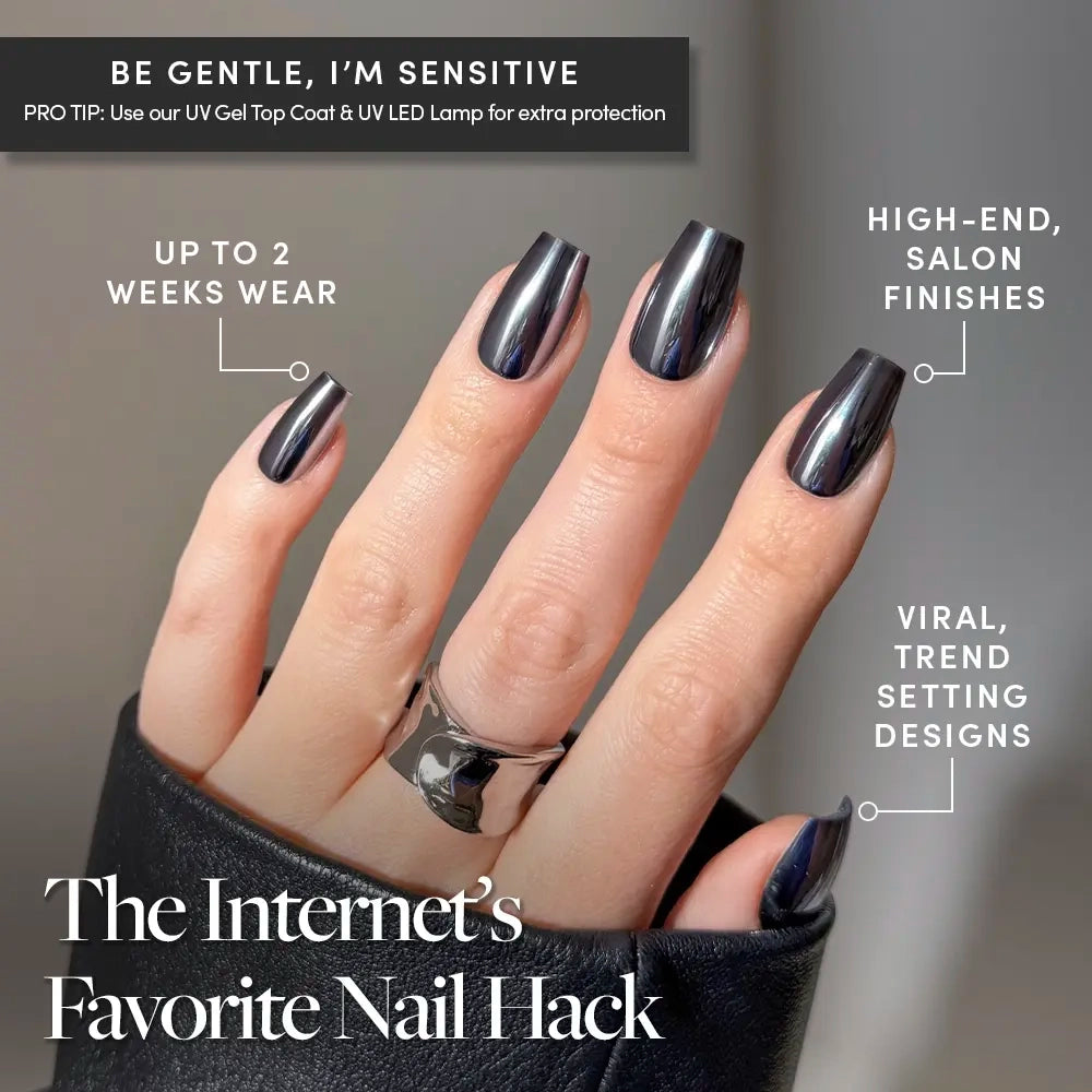 A hand is shown wearing glamnetic’s Gunmetal press-on nails, featuring a shiny, mirrored black coffin shape with a bold silver chrome finish. Text highlights trendsetting designs, high-end finishes, and up to 2 weeks of wear. A chunky silver ring on the thumb completes the look of these modern nails. - Product image