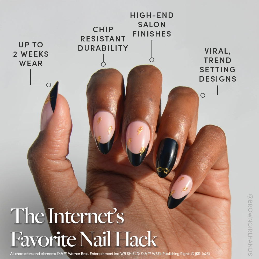 A hand with long, almond-shaped nails features glamnetic Harry Potter™ black French tip press-ons with pink and gold accents. Enjoy salon-quality durability, trendy designs, and up to 2 weeks of wear. - Product image