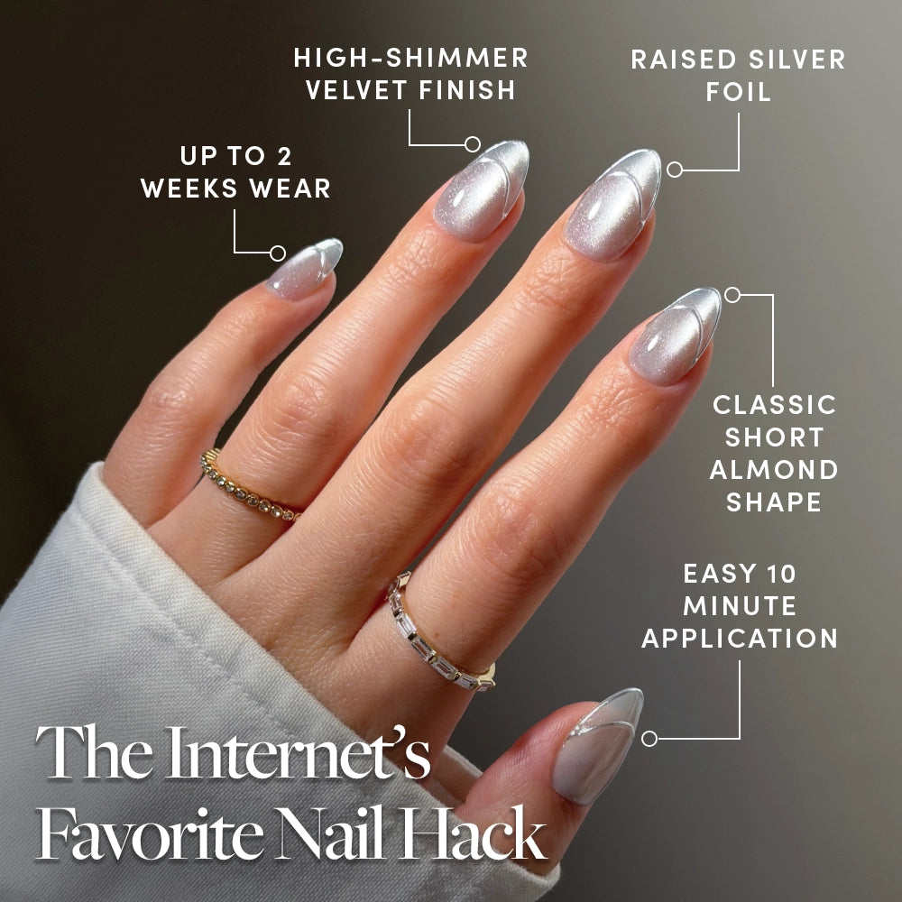 A hand with short, almond-shaped, high-shimmer silver nails—glamnetic’s “Heavenly Metal” press-ons—wearing three rings. Labeled features highlight silver shimmer nails, silver foil, almond shape, easy application of glamnetic press-on nails, and up to two weeks of wear. Text reads: The Internet’s Favorite Nail Hack. - Product image