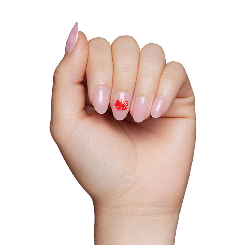 A hand with oval, light pink manicured nails by glamnetic. The ring finger features a red Hello Kitty® face with a bow, as an accent from the vegan & cruelty-free Hello Kitty® set. - Product image