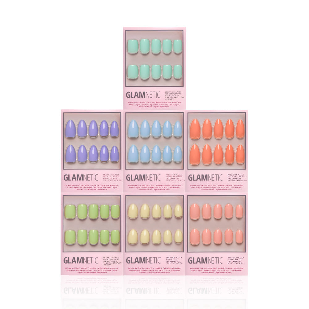 Six boxes of glamnetic press-on nails from the Hello Spring Collection are stacked in a pyramid, each box displaying glossy pastel shades like mint green, lavender, blue, peach, light green, and coral orange. - Product image