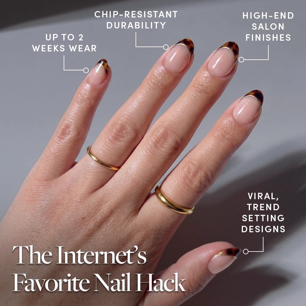 A hand with gold rings shows manicured short oval nails in the "High Standards" tortoiseshell French tip design by glamnetic. Enjoy up to 2 weeks wear, chip-resistant durability, salon-quality finish, and trend-setting viral press-on nails. - Product image
