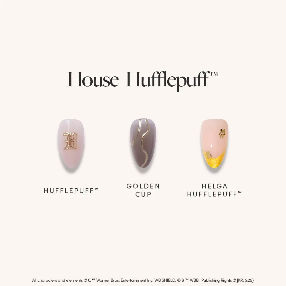 The glamnetic House Hufflepuff™ set features three artificial nails: a beige nail with a gold H, a gray nail with a gold wavy stripe, and an almond-shaped nail with a yellow glitter tip and small black symbol. Text reads House Hufflepuff™.