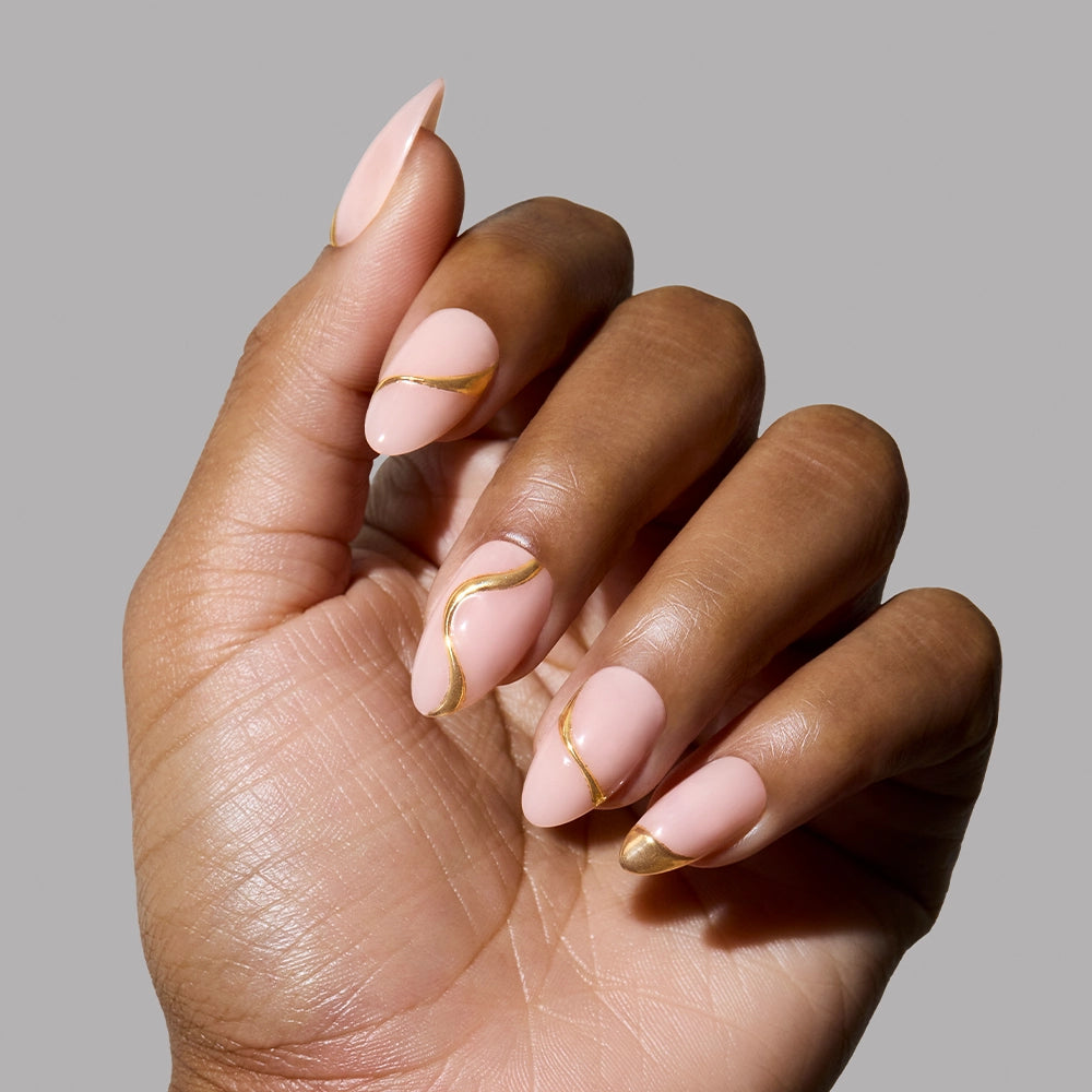 A close-up of a dark-skinned hand wearing the "I Am A Rich Man?" press-on nails, highlighting the dimensional gold accents with modern sculptural curves on a matte pink base.
- Product image