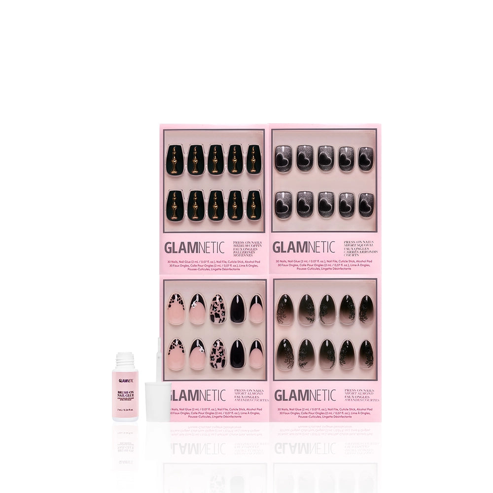 Four sets of glamnetic In The Shadows press-on nails in pink boxes, displaying chic black, nude, and pink coffin nail art, are arranged with a small nail glue bottle in front on a white background. - Product image