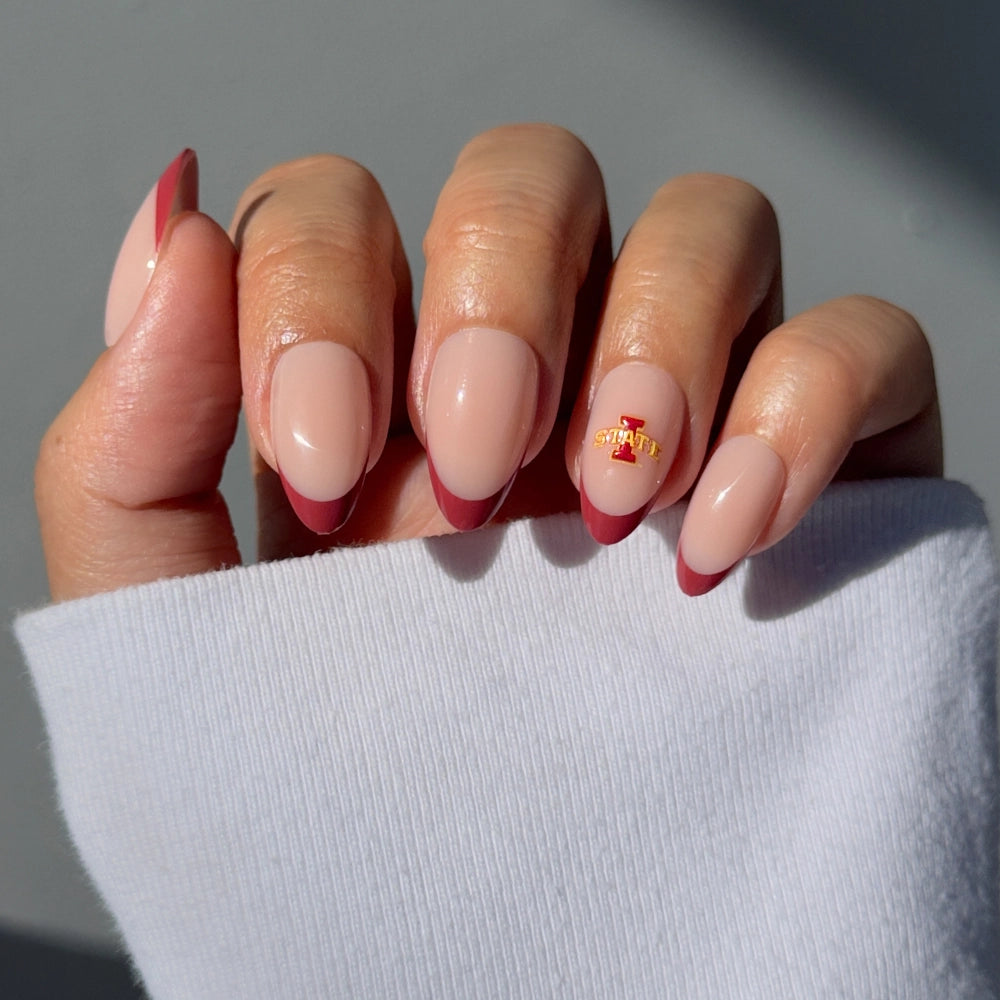 Show off your Cyclone pride with the glamnetic Iowa State Cyclones Press-On Nail Set—salon-quality, almond-shaped nails with a nude base, dark pink French tips, and a red-and-yellow STATE logo. Pairs perfectly with a white long-sleeve top!.