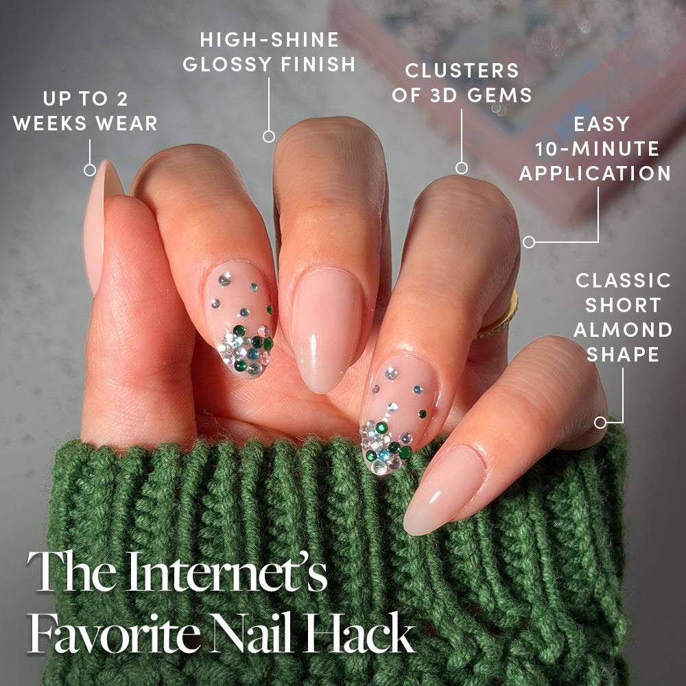 Jewel Thief - Glamnetic Jewel Thief short almond-shaped press-on nails in a glossy nude finish, featuring clusters of green and clear 3D gems, offering a 10-minute application time and up to two weeks of wear.