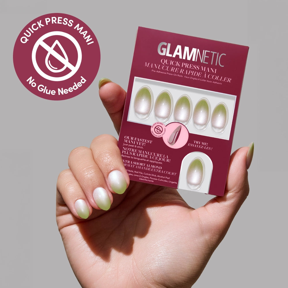 A hand with iridescent, almond-shaped Lime Beam press-on nails holds a glamnetic Quick Press Mani package. A round badge reads Quick Press Mani - No Glue Needed with a crossed-out glue icon, showing these easy stick-on nails.
