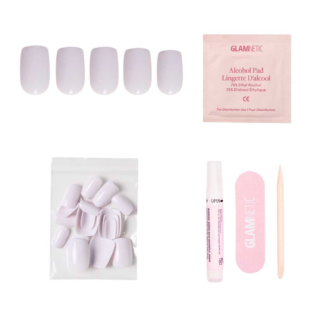 The Lilac Gray nail kit by glamnetic includes pale pink squoval nails with a glossy finish, an alcohol pad, nail file, cuticle stick, glue, and extra nails in a clear bag—neatly arranged on a white background. - Product image