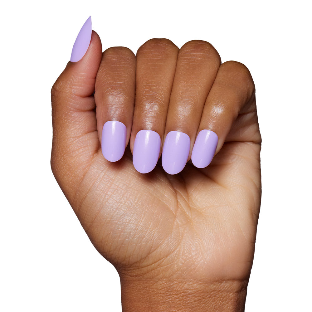 A hand with medium brown skin displays neatly manicured glamnetic Lilac press-on nails, featuring glossy pastel lavender polish, against a white background. - Product image