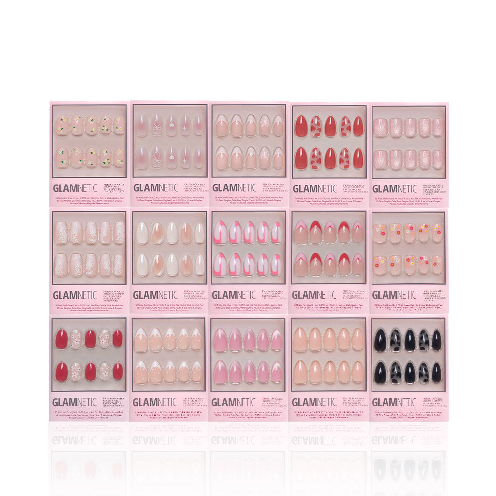 Sixteen sets from glamnetics Love In Bloom Collection are arranged in four rows, featuring unique designs—pinks, reds, trendy patterns, heart accents, and short almond shapes—for a stylish manicure display.