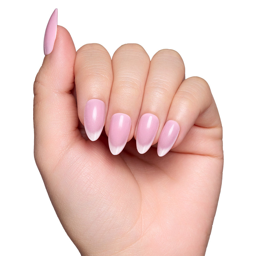 A hand with neatly manicured almond nails, featuring glamnetic’s Lovers Blush set—a blush-toned base and white tips in an almond shape—shown against a white background. - Product image