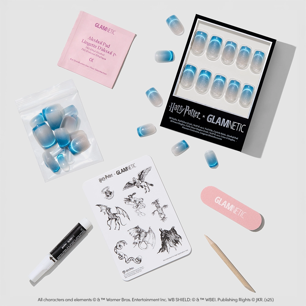 A flat lay of the glamnetic Lumos press-on nails kit, featuring velvet blue gradient nails, an alcohol pad, nail glue, nail file, wooden stick, and magical creature stickers. - Product image