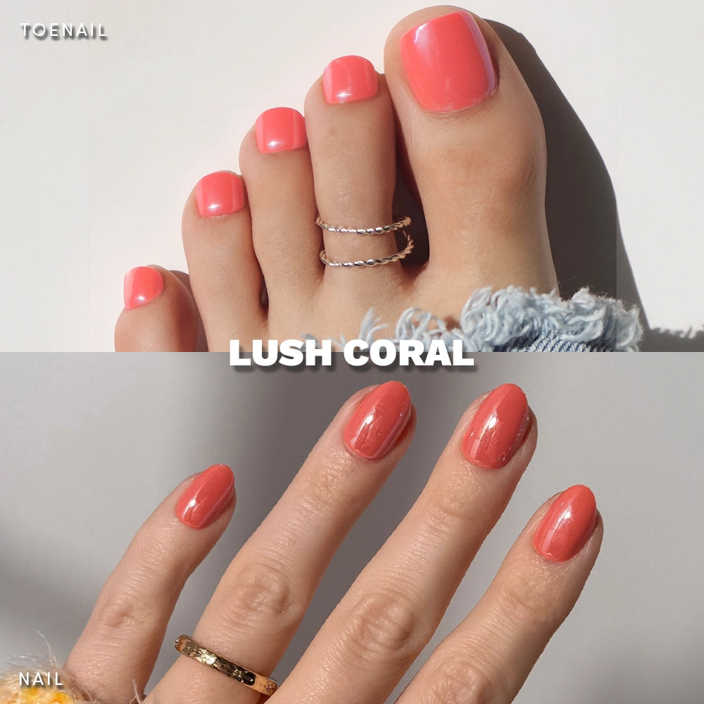 Close-up of glamnetic's Lush Coral Mani & Pedi—glossy coral pink press-ons with a glazed finish. Nails pop against a neutral background; toes wear rings and denim, hand wears gold. Perfect for fans of coral mani and pedi sets. - Product image