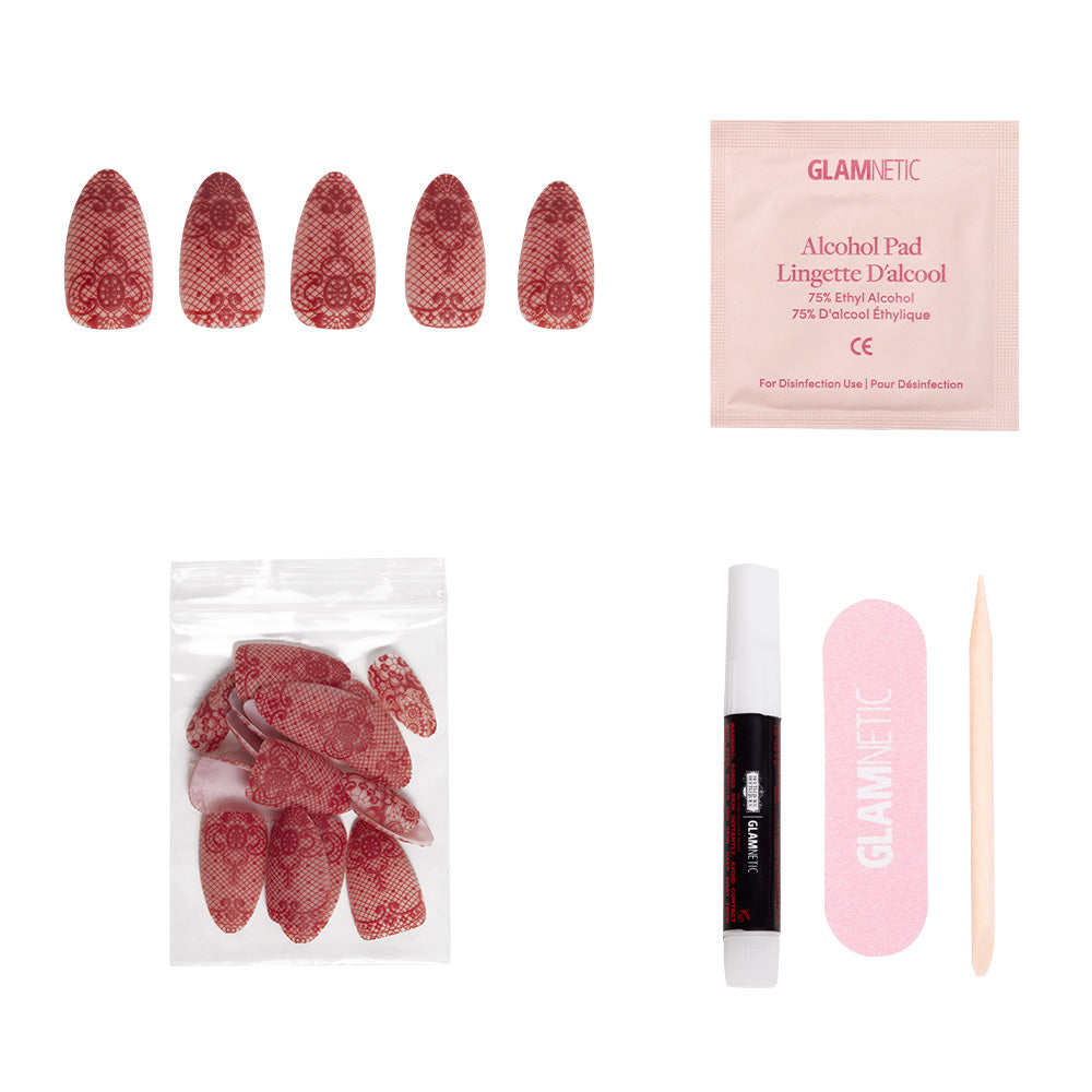 The glamnetic Lydia set includes 3D-raised red lace press-on nails, extra nails, nail glue, an alcohol pad, a pink nail file, and a wooden cuticle stick displayed on a white background. - Product image