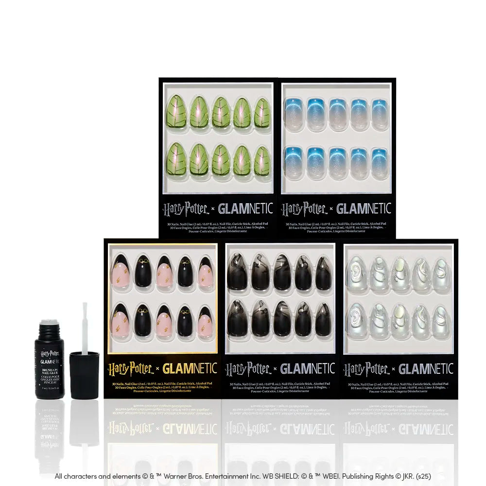 Six sets of glamnetic Magic & Mystery nails are displayed in themed packaging with a bottle of nail glue and an applicator, all arranged on a reflective white surface for the ultimate wizarding manicure. - Product image