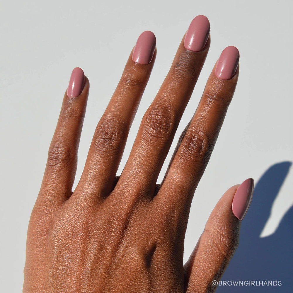 A hand with medium brown skin and neatly manicured nails painted in Mauve Mood by glamnetic is shown against a plain white background, with the @BROWNGIRLHANDS logo in the bottom right corner. - Product image