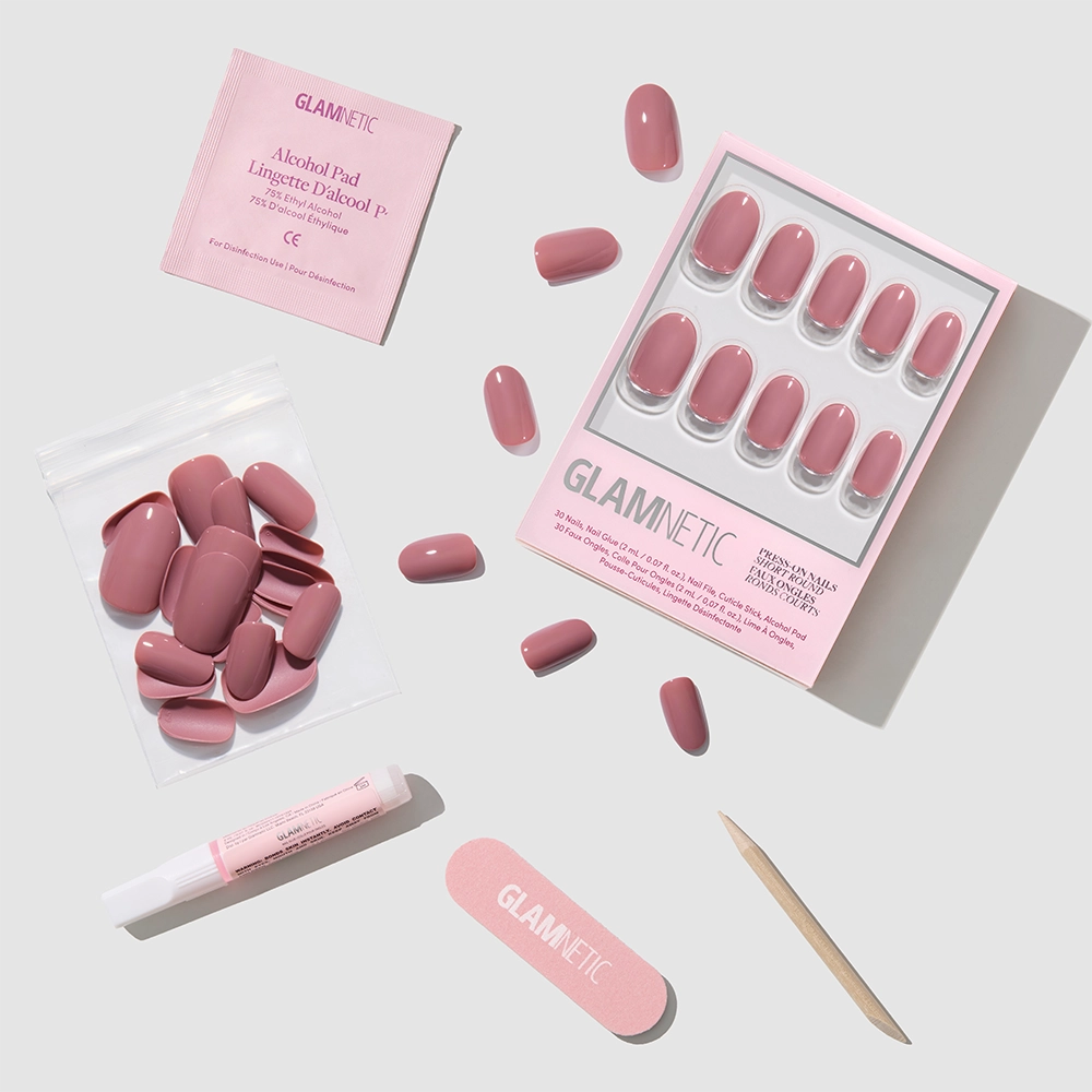 A flat lay of glamnetic's Mauve Mood Press-On Nails kit, featuring salon-quality essentials—nails, extra nails, a nail file, cuticle stick, glue, and an alcohol pad—neatly arranged on a light background. - Product image