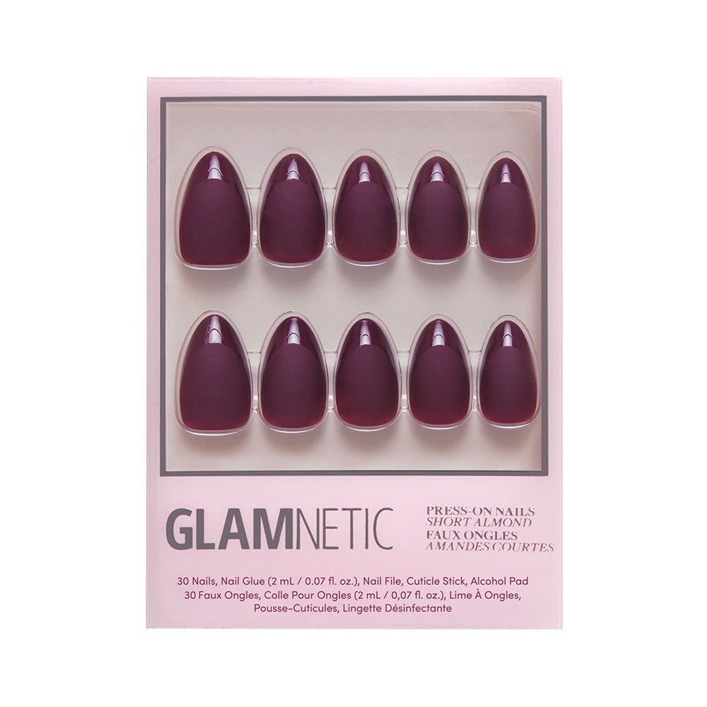 A box of glamnetic Merlot press-on nails in short almond shape with a deep purple matte finish, arranged in two rows of five, featuring product details and glamnetic branding on the packaging. - Product image